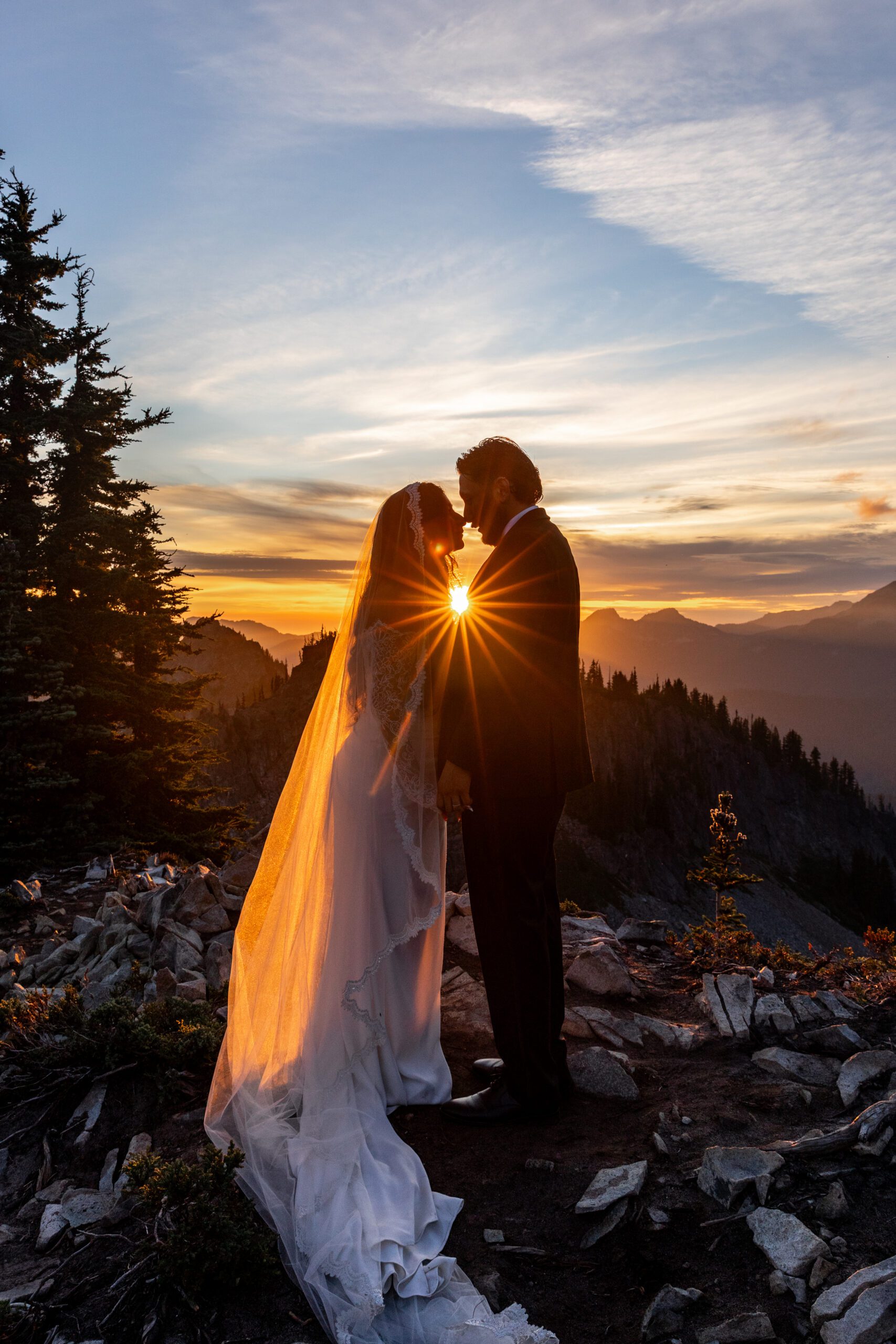 A couple standing facing each other are eloping at Mount Rainier with sunset rays in between them